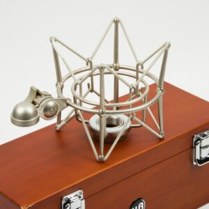 A metal microphone shock mount rests on a wooden case