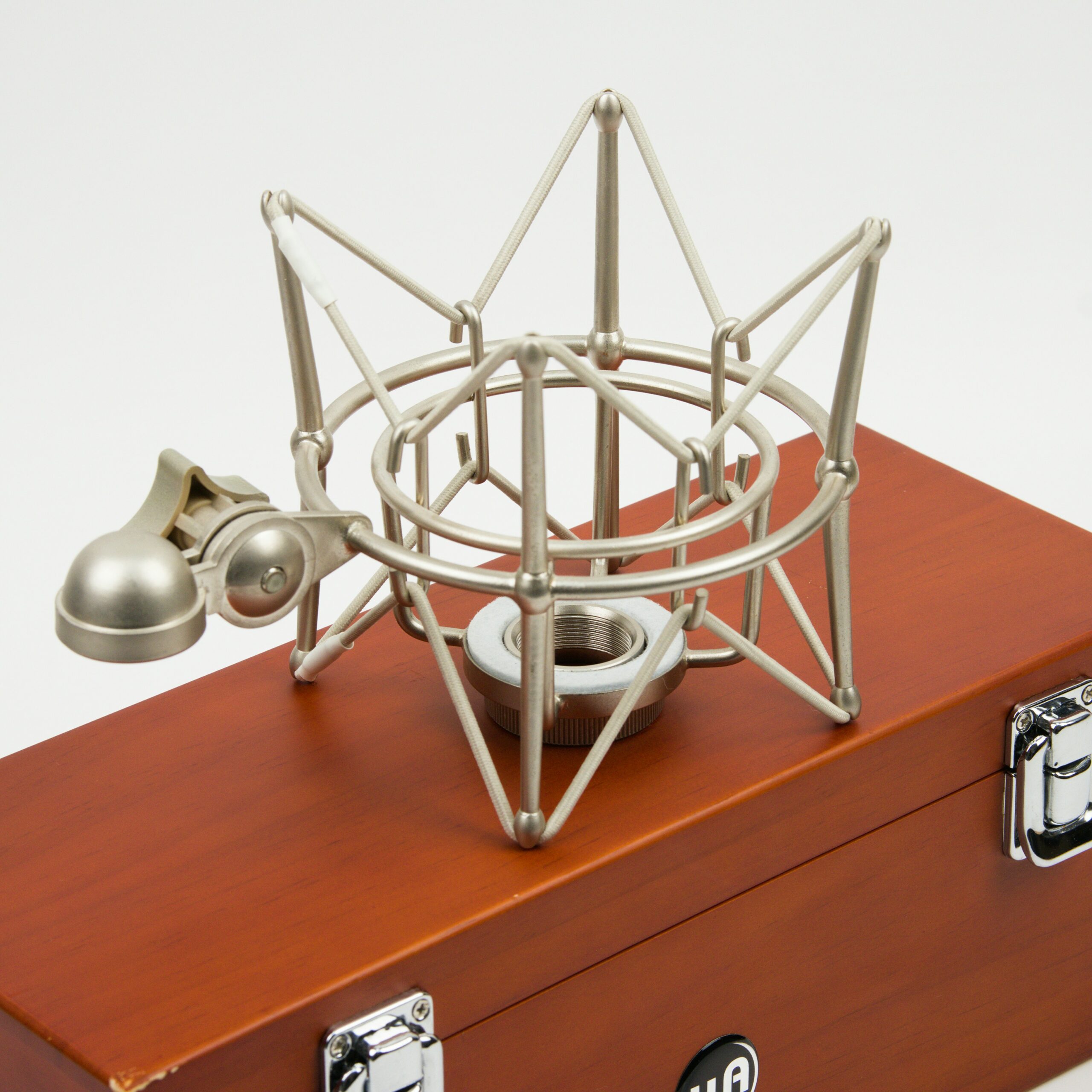 A metal microphone shock mount rests on a wooden case